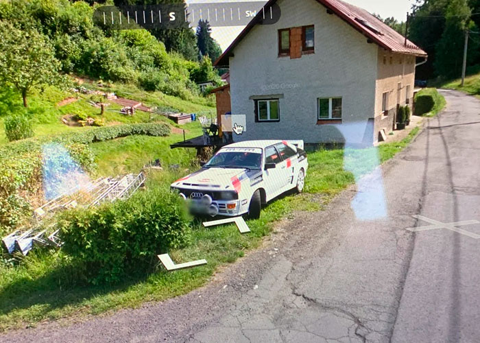 Vintage rally car parked beside a rural house on a quiet road, highlighting unlikely events people experienced outdoors.