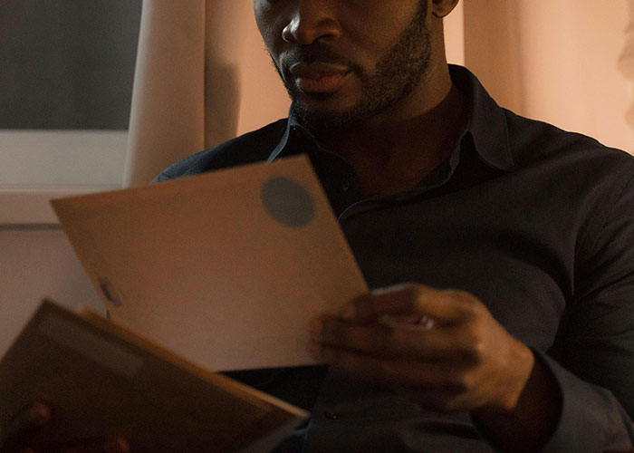 Man reading mail indoors at night, illustrating improbable events people experienced in everyday life scenarios.