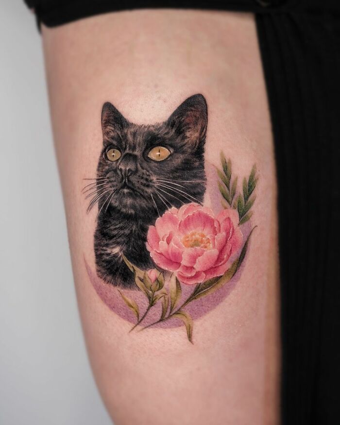 Cute pet portrait tattoo of a black cat paired with a pink flower on forearm.