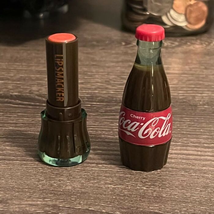 Lip Smacker cherry Coca-Cola novelty lip balm and matching small Coca-Cola bottle on wooden surface for dopamine hit.