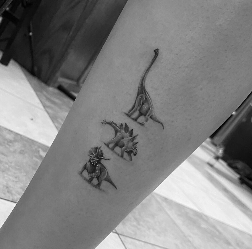 Single needle tattoos of three dinosaurs on a person's calf, showcasing detailed ink art.