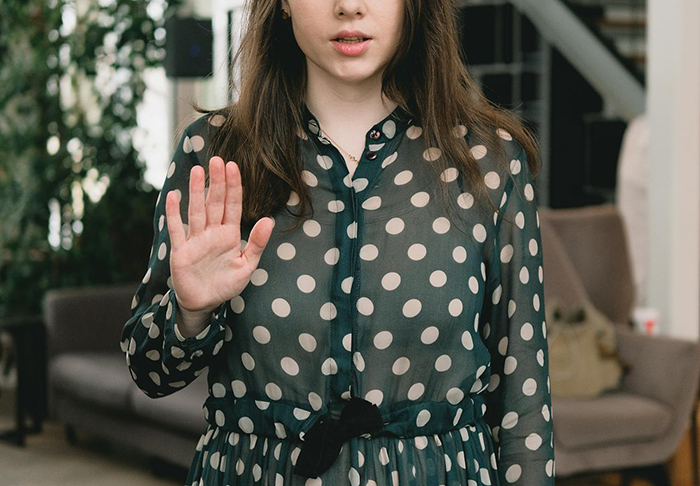 Woman in a polka dot dress raising her hand, symbolizing people in their 40s, 50s, and 60s sharing views on Gen Z.