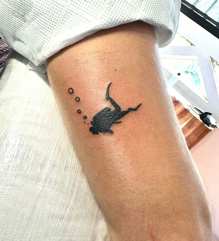 Tattoo of a scuba diver with bubbles on an arm, illustrating unique and uncomfortable tattoo art designs.