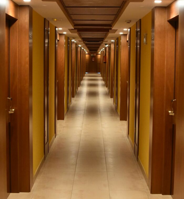 Hotel hallway with closed wooden doors on both sides, evoking unsettling feelings from frightening vacation stories.