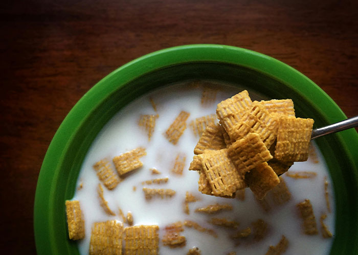 Bowl of cereal with milk and a spoonful of shredded wheat representing strange childhood realities and memories.