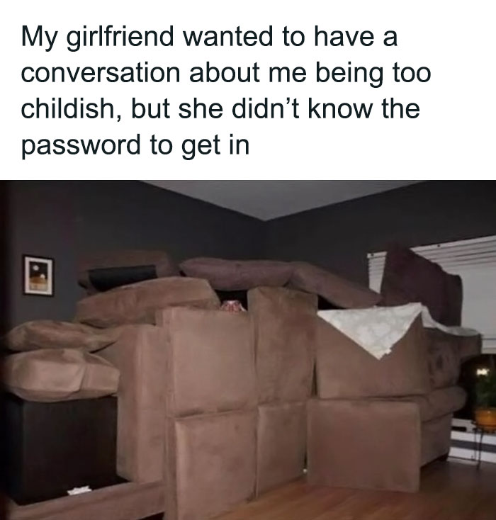 Pillow fort blocking entrance to room, humorously depicting childish behavior; gray walls and wooden floor.