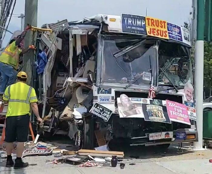 Damaged bus with political signs and workers attempting to fix it, capturing a funny and awkward moment attempt.