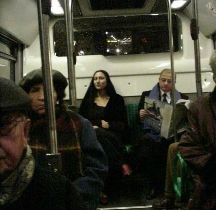 Passenger resembling Mona Lisa sitting quietly on a crowded bus in a random and cringe photo for unique humor.
