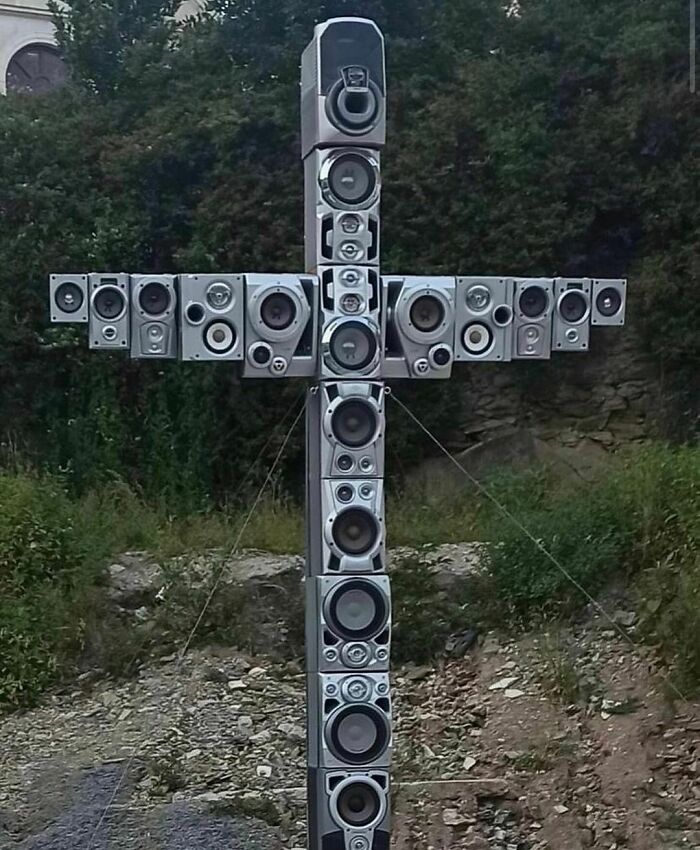 Cross-shaped structure made of random speakers outdoors, showcasing cringe humor for those with a unique sense of humor.