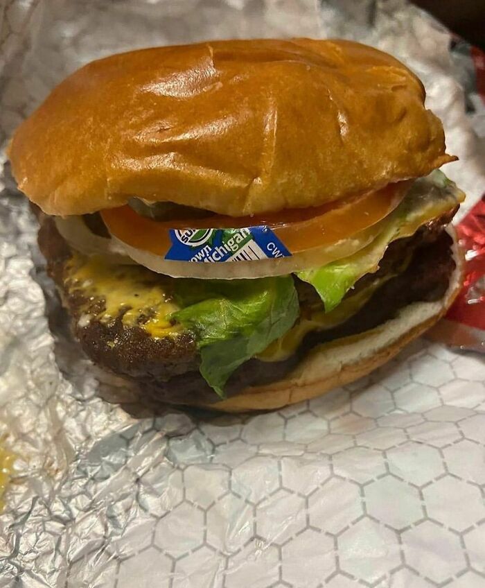 Weird Instagram photo of a burger with a sticker between the bun and toppings.