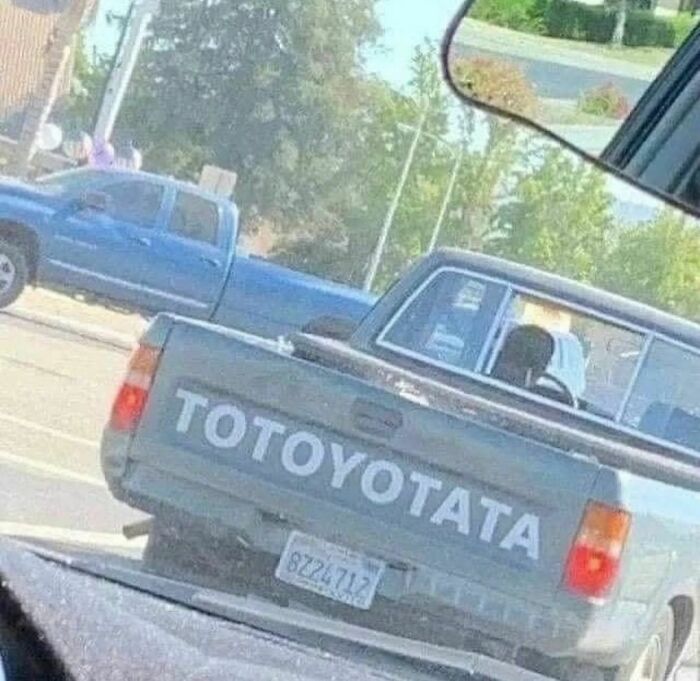 Pickup truck with "TOToyotata" text on tailgate seen in traffic from car window.