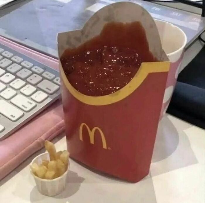 Unusual Instagram photo of fries container filled with ketchup beside a keyboard.