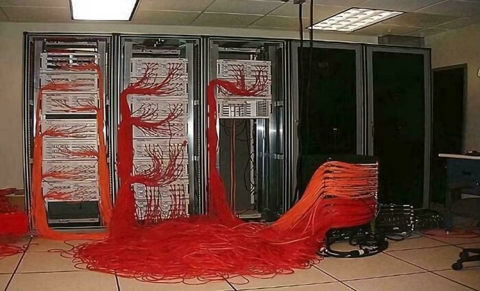 Server racks with tangled red cables spilling onto the floor, illustrating a funny and awkward attempt that didn’t go as expected.