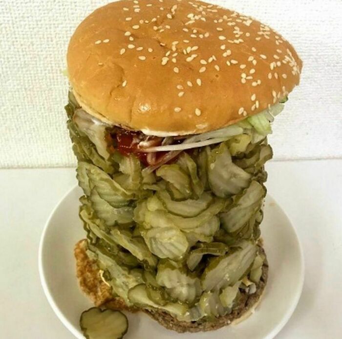 Hamburger burger stacked unusually high with excessive pickles, creating an awkward and painful-to-look-at food photo.