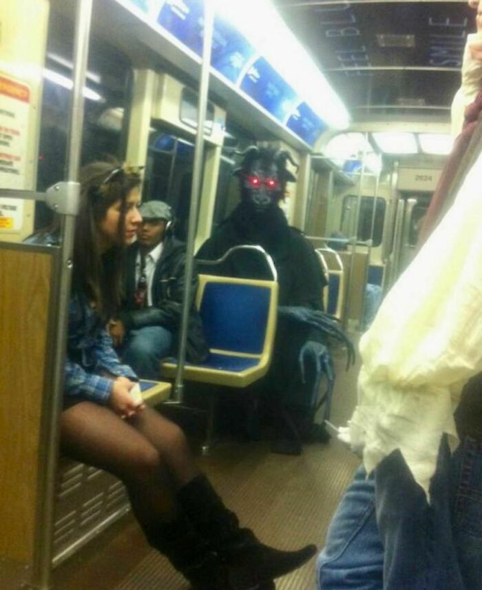 Person on subway sitting across from someone in a demonic costume with glowing red eyes awkward photo moment