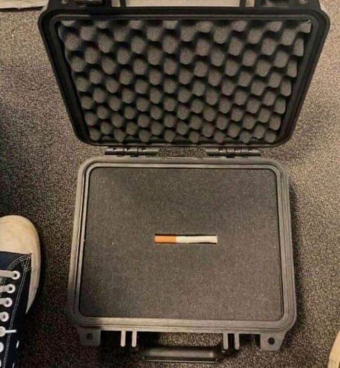 Open empty hard case with a single cigarette inside, creating an awkward photo using unexpected size and placement contrast.