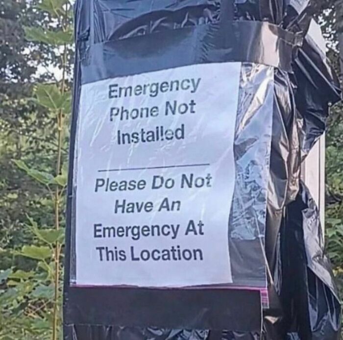 Sign taped to a pole reads emergency phone not installed please do not have an emergency at this location awkward photo.