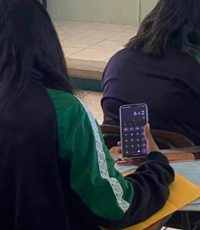 Student using a phone calculator to solve a simple math problem during class, an awkward photo moment captured.