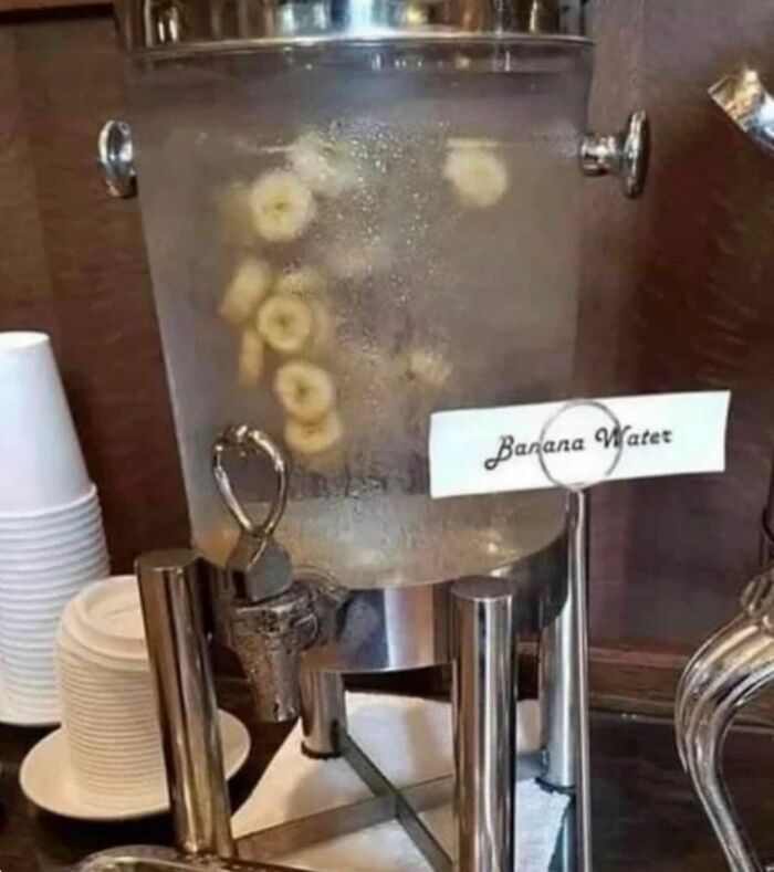 Water dispenser labeled banana water filled with floating banana slices, an awkward photo that is almost painful to look at.