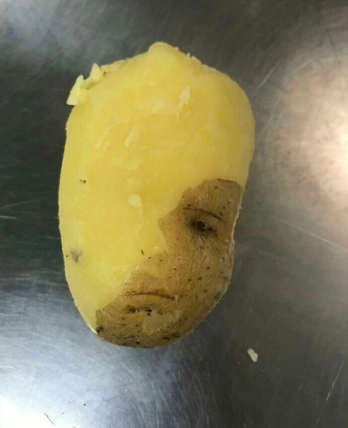 Partially peeled potato resembling a sad human face, one of the awkward photos almost too painful to look at.