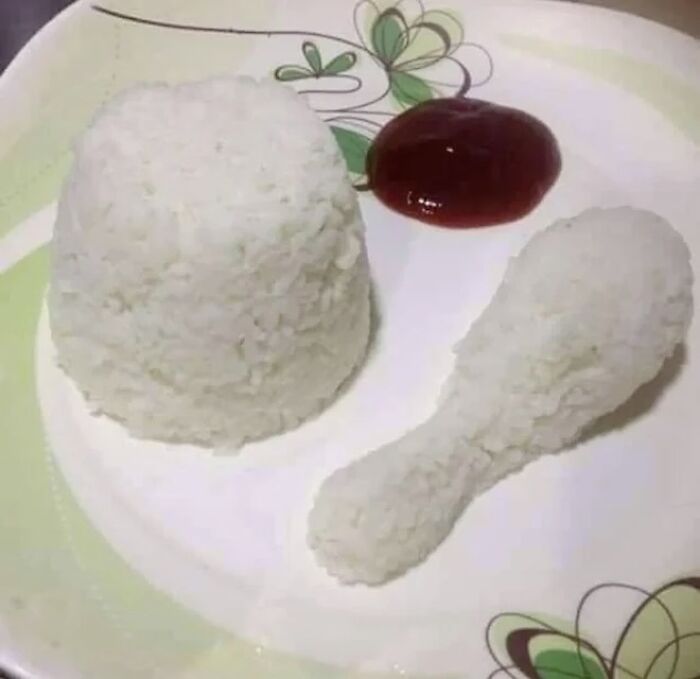 Rice shaped like a chicken drumstick and a mound on a plate with ketchup, an awkward photo sure to catch attention.