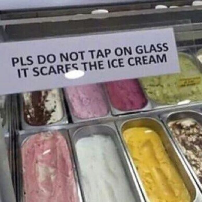 Sign saying do not tap on glass to avoid scaring ice cream displayed in metal containers, awkward photos concept.
