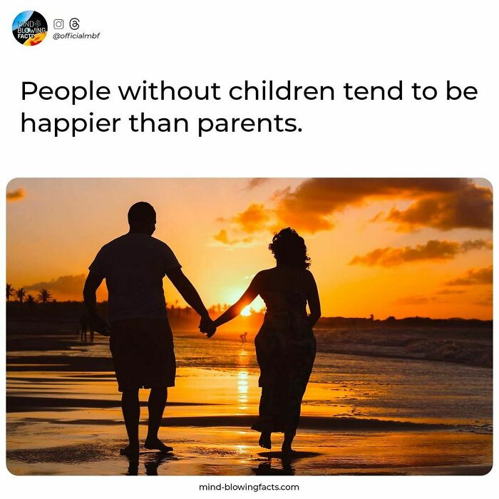 Couple holding hands walking on the beach at sunset, illustrating an amazing fact about happiness and parenthood.
