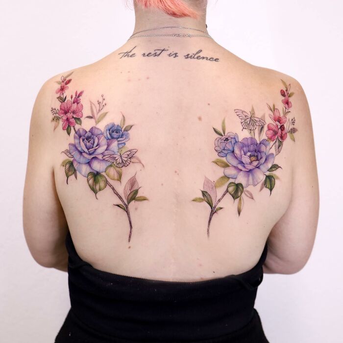 Back tattoo design reminiscent of watercolor, featuring vibrant floral patterns and butterflies.