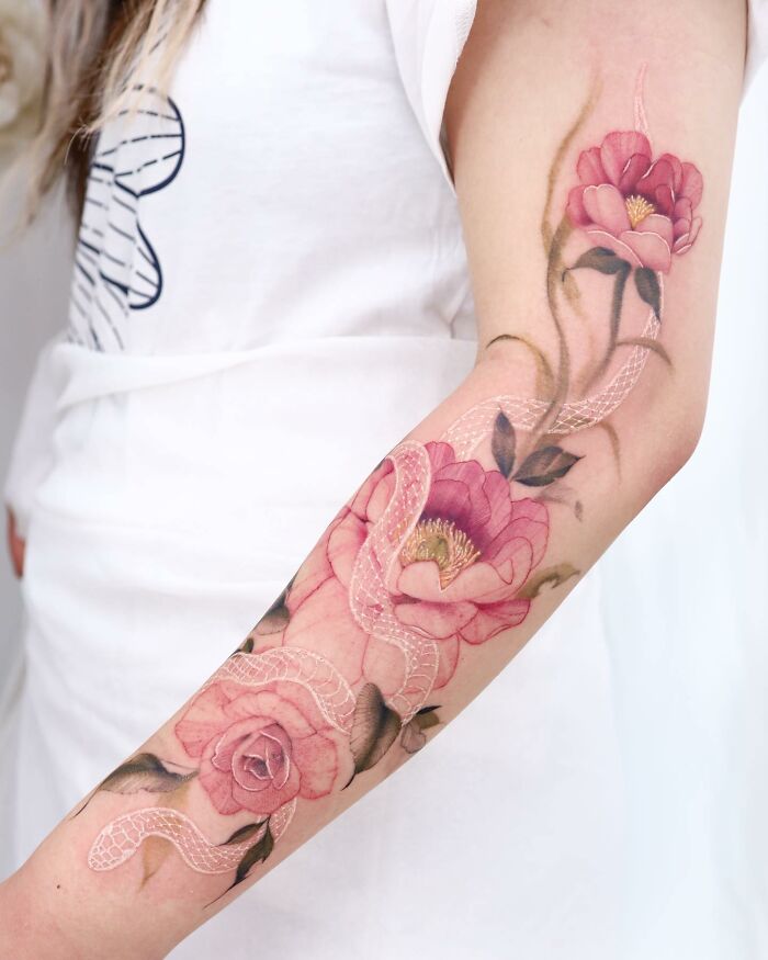 Watercolor tattoo design featuring pink roses and a white snake on a person's forearm.