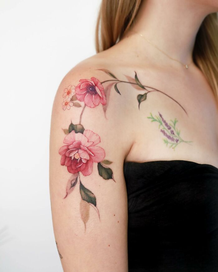 Watercolor-inspired tattoo design with pink flowers on a woman's shoulder.