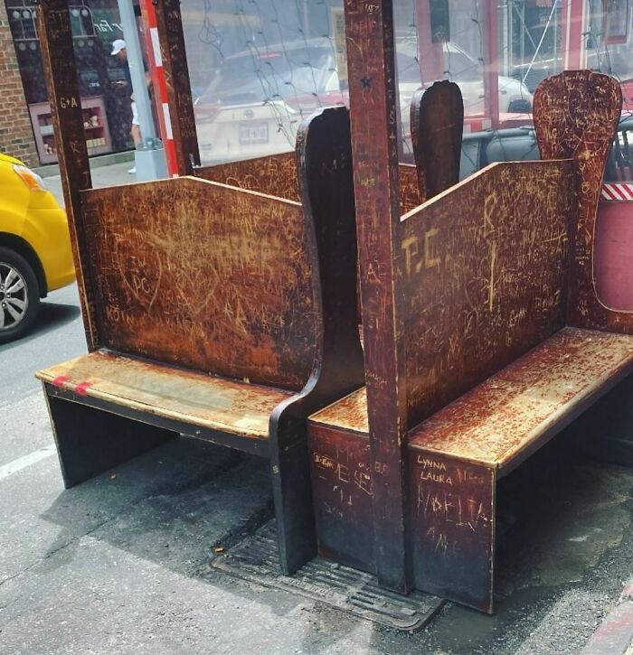 Weathered wooden booth seats, covered in graffiti, left on the curb as a discarded NYC treasure.