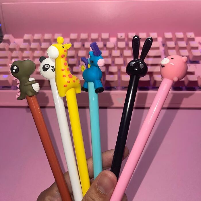 Fun animal pens adding a playful touch to your work supplies, against a pink keyboard backdrop.