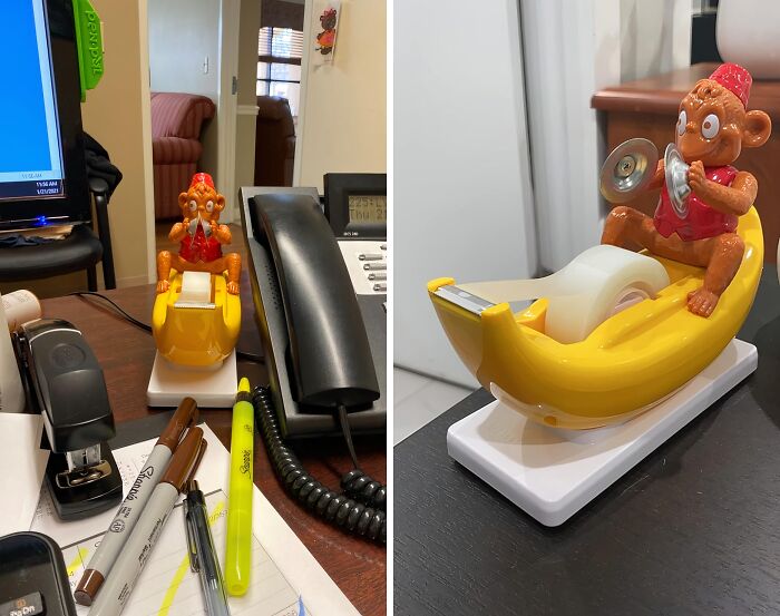 Monkey tape dispenser on desk with pens, stapler, and phone, adding fun to work supplies.