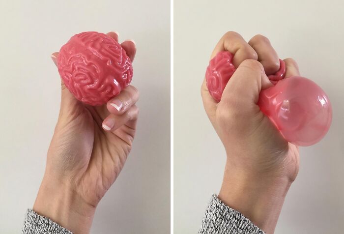 Hand squeezing a pink stress ball shaped like a brain to make Monday feel less daunting with effective work supplies.