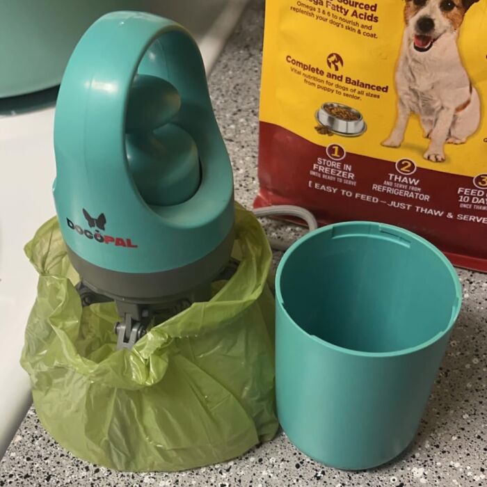 Pet gadget for cleanup with a teal design, shown on a countertop next to a dog food bag.