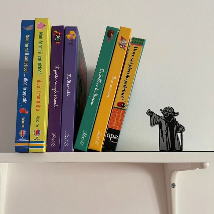 Children's books neatly arranged on a shelf next to a Yoda figurine, creating a playful workspace environment.