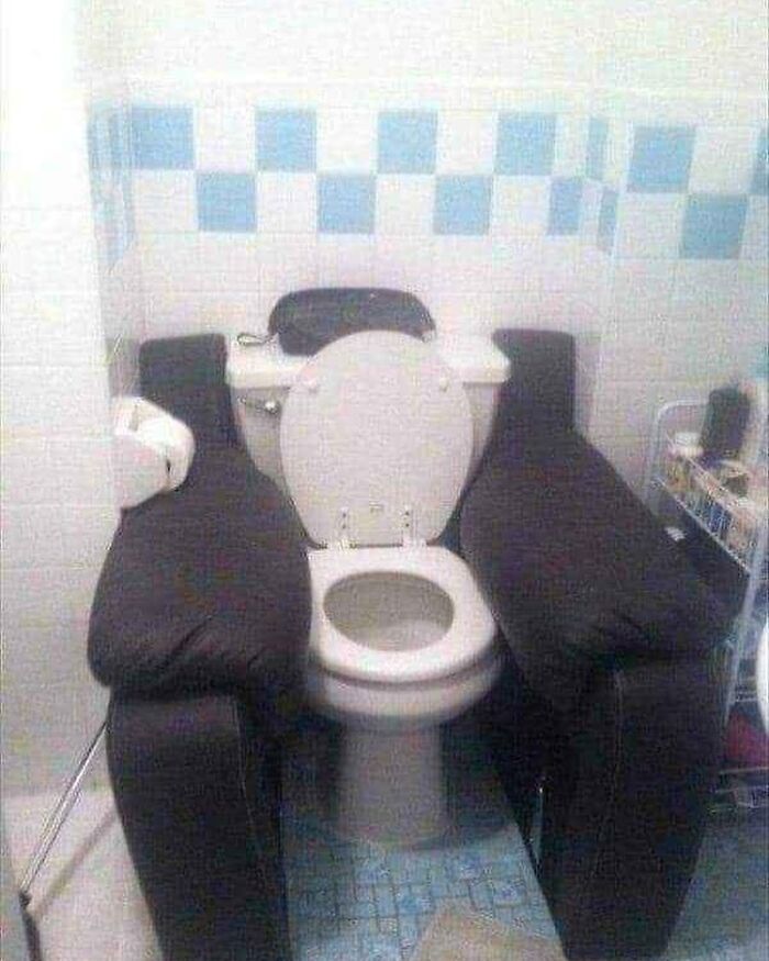 Toilet with armchairs on each side, creating a humorous setup.