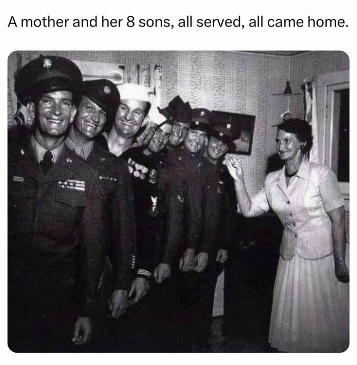 A black and white photo of a mother with her eight sons in military uniforms, a rare historical family moment.