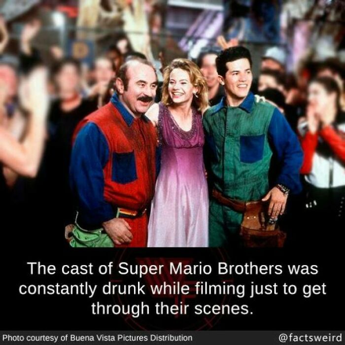 The cast of Super Mario Brothers smiling together on set in colorful costumes.