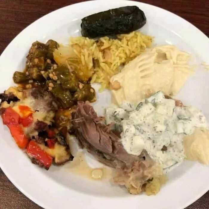 A plate with unappetizing food, including stuffed grape leaves, rice, and a mix of vegetables and meat.