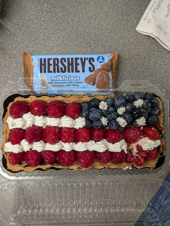 Fruit tart attempt with raspberries and blueberries arranged like an American flag, but part is smashed and messy.