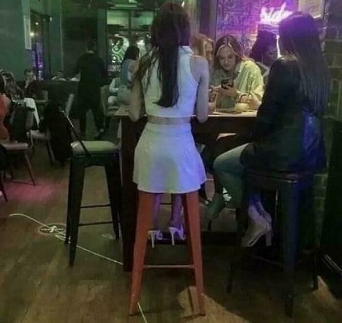 Woman sitting on a tricky chair optical illusion, four people at a dining table.