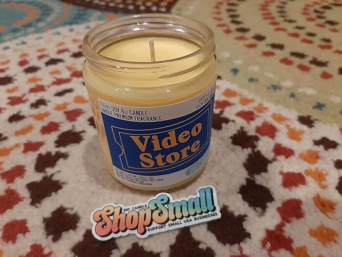 Candle labeled "Video Store" on a patterned background, with a "Shop Small" sticker in front.