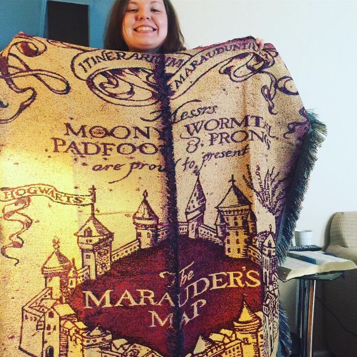 Smiling person holding a Marauder's Map blanket, one of 50 random things capturing attention.