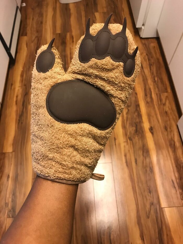 Weird thing: a bear paw oven mitt being worn in a kitchen.