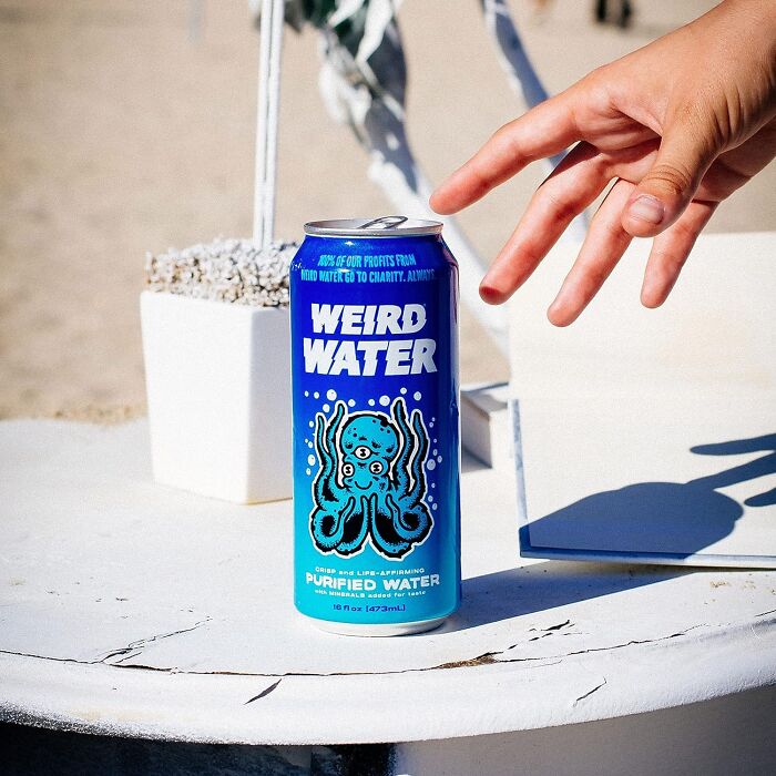 A can of Weird Water with an octopus design on a table, reaching hand nearby, caught and kept attention.