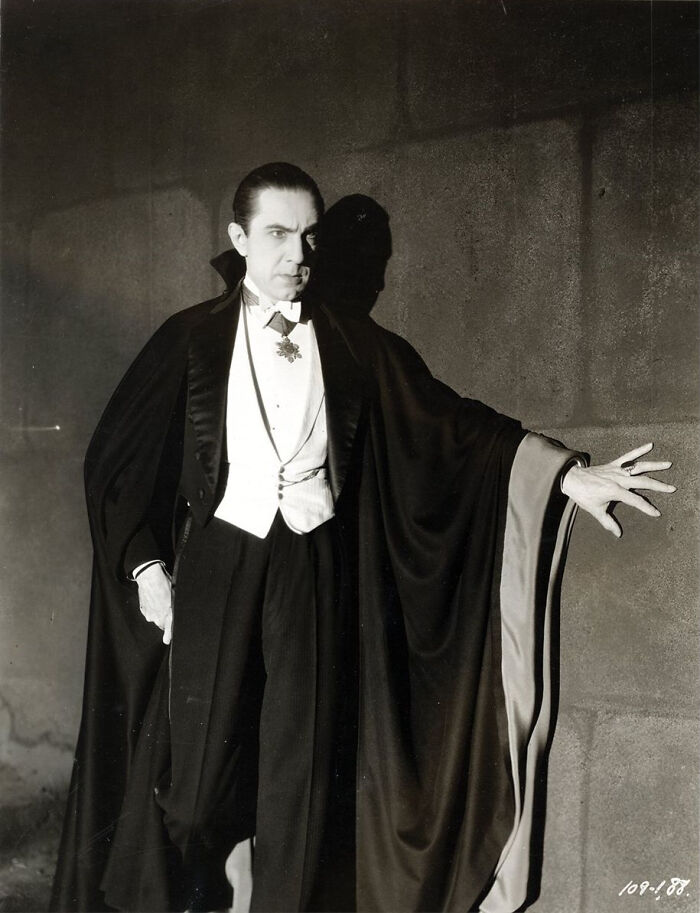 A man in a classic vampire costume with a cape, embodying dad humor in a dramatic pose.