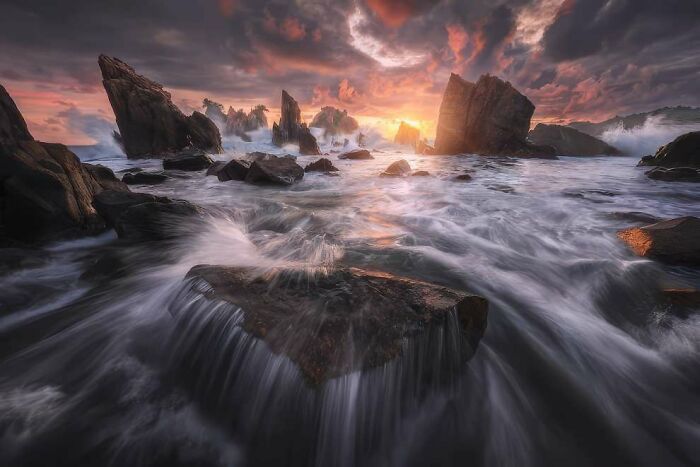 Breathtaking landscape photo of rocky shoreline with dramatic sunset and waves captured from 2024 ReFocus Awards.