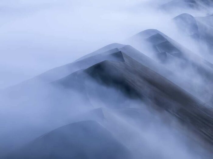 Misty mountain peaks enveloped in fog showcasing breathtaking landscape photography from 2024 ReFocus Awards.