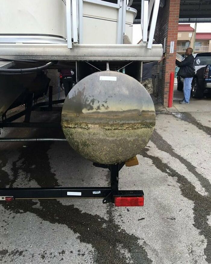 Boat trailer tire covered in dirt and algae with a reflection resembling a landscape, slightly amusing and intriguing photo.